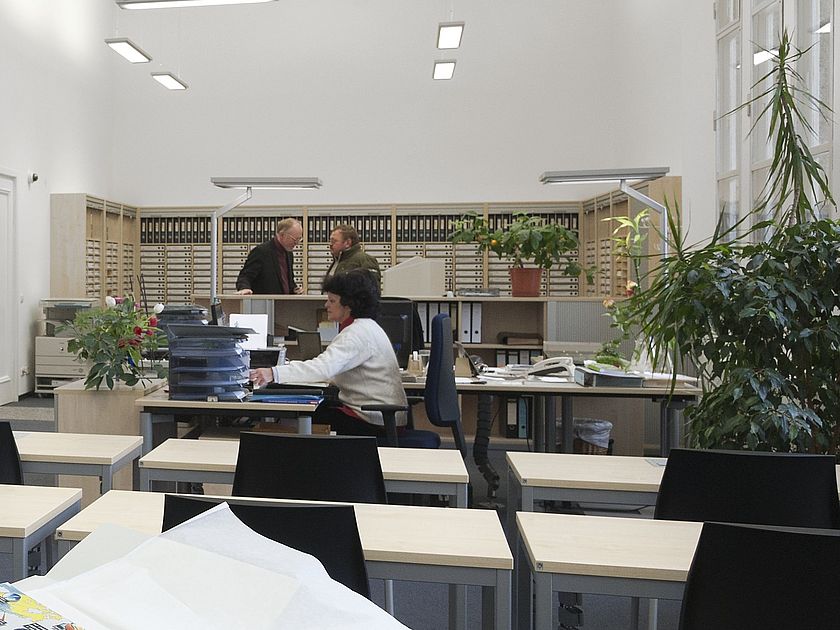 Besucher beim Betrachten eines Plans, Blick in den Lesesaal.