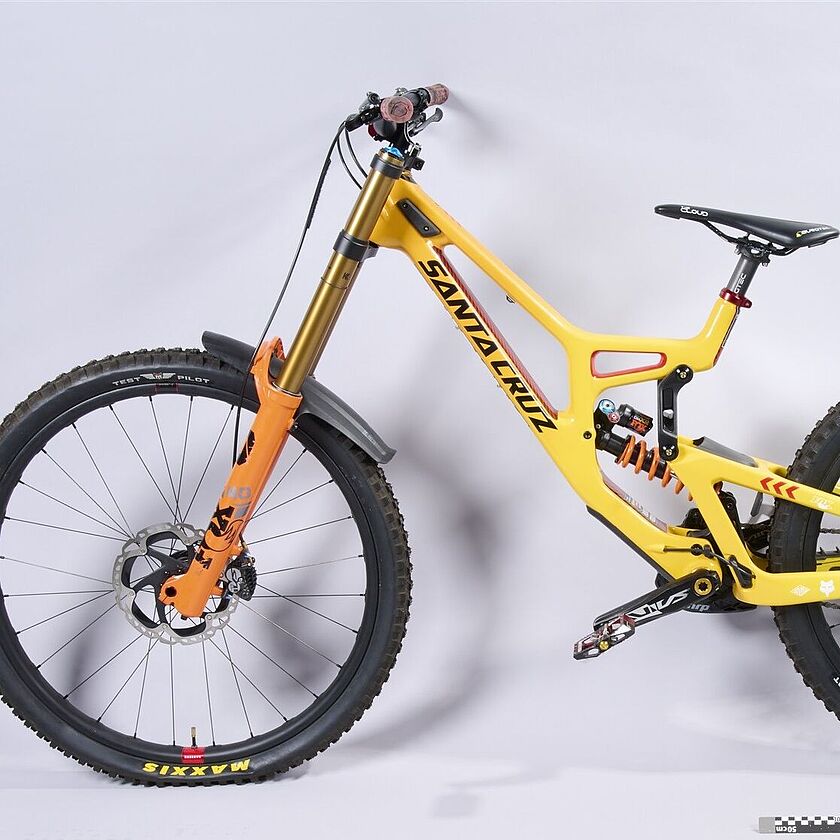 2025-175_Mountainbike Mountainbike von der Seite fotografiert. Besonderheiten: gelber Rahmen, hohe Federung, große Reifen. Es ist deutlich, dass es sich um ein stabiles und optimiertes Sportgerät handelt.