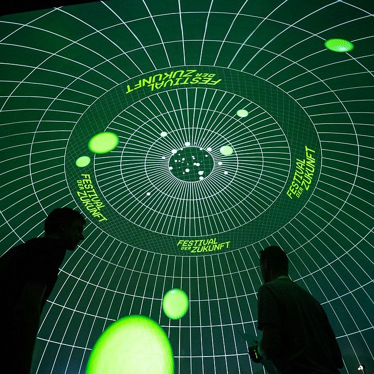 Besucher vor Projektion: Festival der Zukunft Schriftzug mit Kreisen