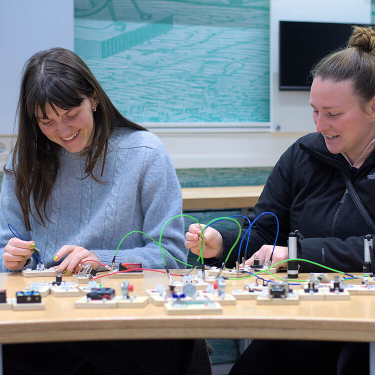 Zwei Frauen bauen einen Stromkreis auf.