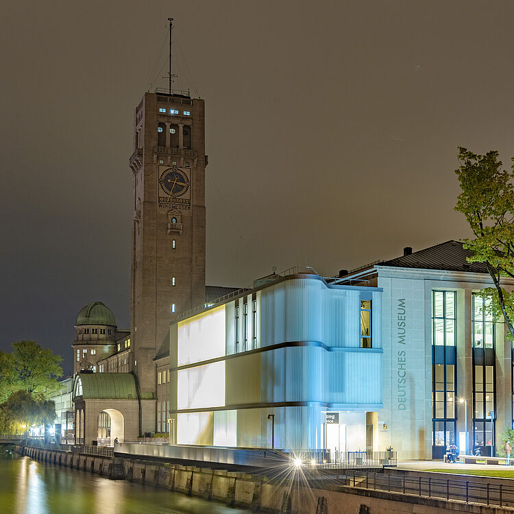 Nachtaufnahme des Deutschen Museums, mit Museumsturm und Eingangsbereich.