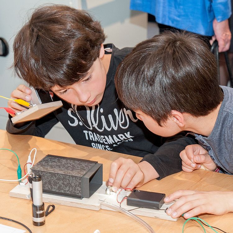 Zwei Jungen testen einen selbstgebauten Lautsprecher.