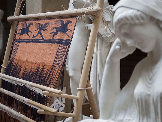 Warp-weighted loom with reconstruction of a fabric with reconstructed Penelope sculpture in the front